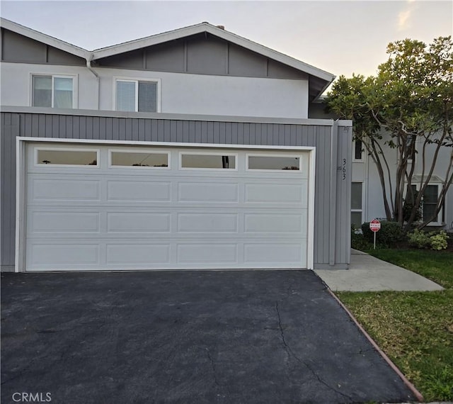 garage at dusk featuring driveway