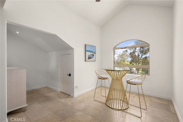 tiled dining space featuring high vaulted ceiling