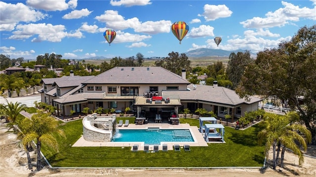 rear view of house featuring a lawn, a patio, a mountain view, and pool water feature