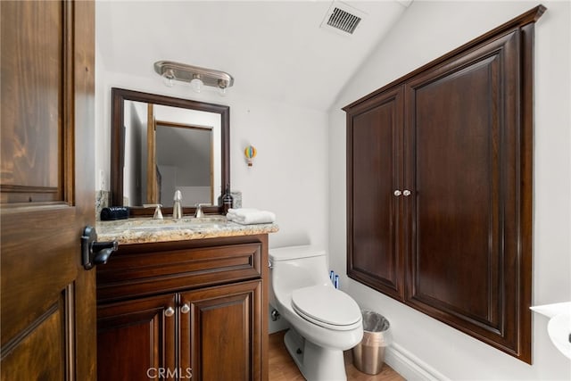 bathroom with toilet, vanity, and vaulted ceiling