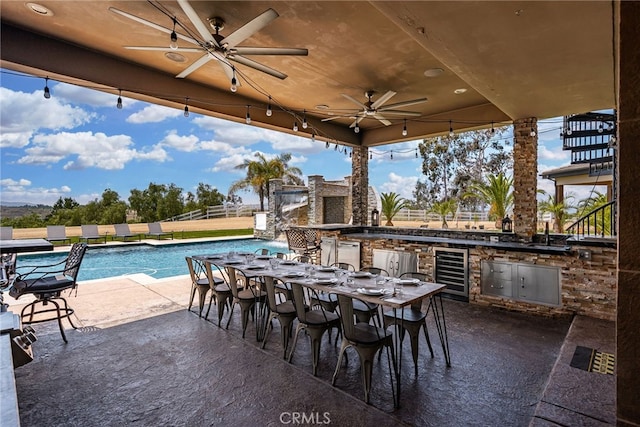 view of patio featuring a fireplace, an outdoor kitchen, and wine cooler