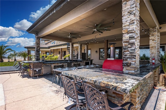 view of patio with ceiling fan and a bar