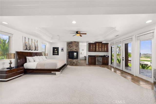 bedroom with multiple windows, access to outside, beverage cooler, and a raised ceiling