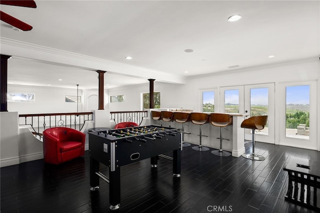 game room with decorative columns, crown molding, dark hardwood / wood-style floors, and indoor bar