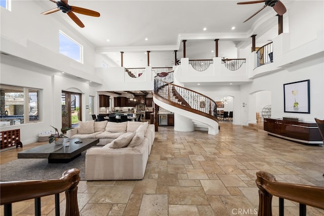 living room with ornamental molding, a healthy amount of sunlight, and ceiling fan with notable chandelier