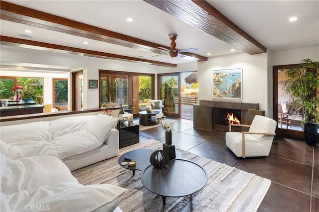 living area with recessed lighting, beamed ceiling, and a lit fireplace