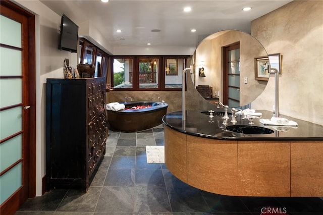 full bath featuring recessed lighting, a freestanding tub, stone finish floor, and vanity