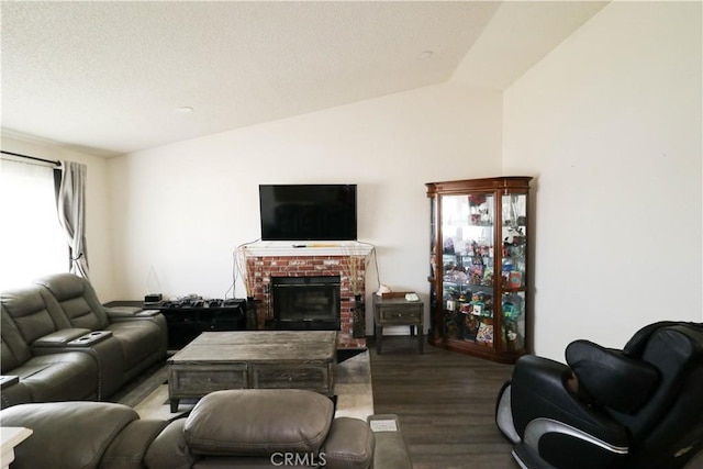 living room featuring dark hardwood / wood-style flooring, a brick fireplace, and lofted ceiling