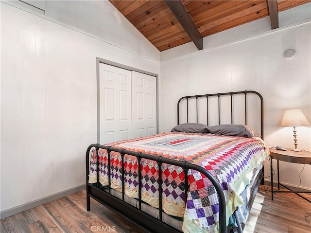 bedroom featuring baseboards, vaulted ceiling with beams, wood finished floors, a closet, and wood ceiling