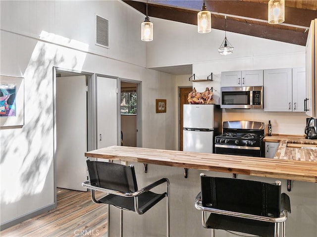 kitchen with visible vents, appliances with stainless steel finishes, butcher block countertops, and hanging light fixtures