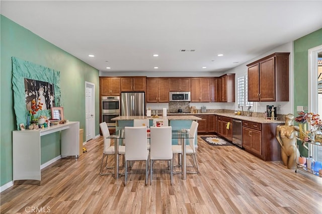 kitchen featuring a sink, stainless steel appliances, a kitchen bar, and light wood-style floors