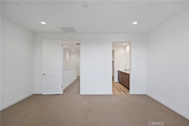 unfurnished bedroom featuring light colored carpet and ensuite bath