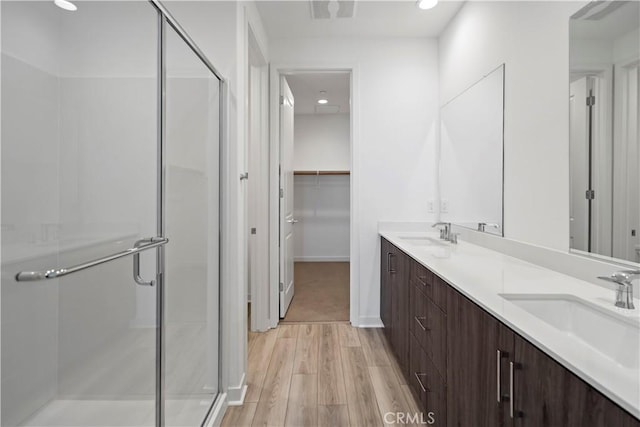 bathroom featuring wood-type flooring, an enclosed shower, and vanity