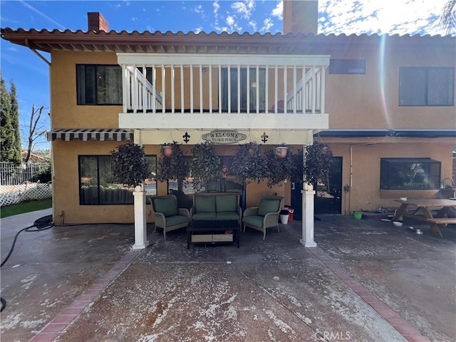 rear view of house with a balcony, a patio area, and an outdoor hangout area