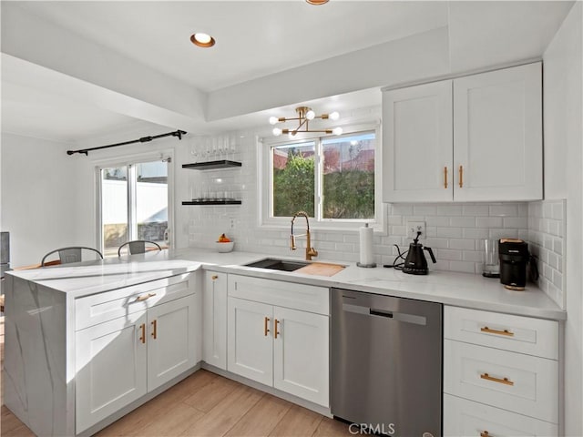 kitchen with white cabinetry, kitchen peninsula, sink, stainless steel dishwasher, and decorative backsplash