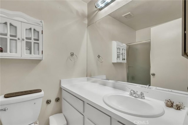 full bath featuring visible vents, toilet, vanity, and a shower with door