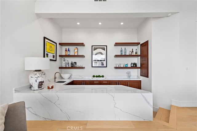 bar featuring sink and light stone countertops