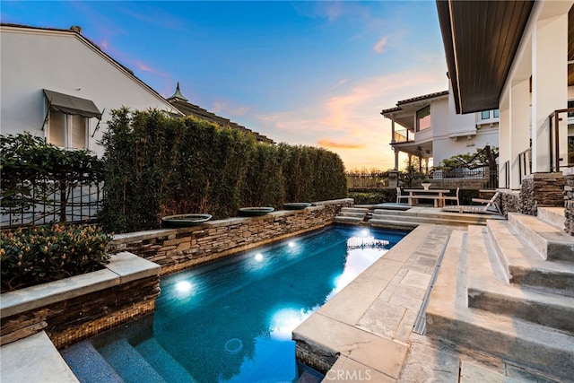 pool at dusk featuring a patio area