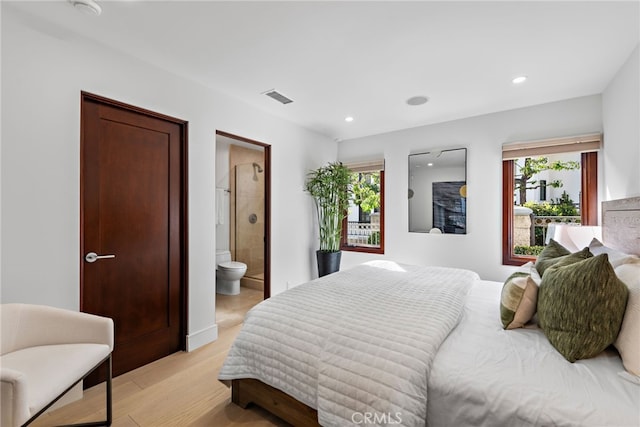 bedroom with light wood-type flooring and ensuite bath