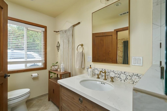 bathroom with toilet, vanity, and parquet flooring