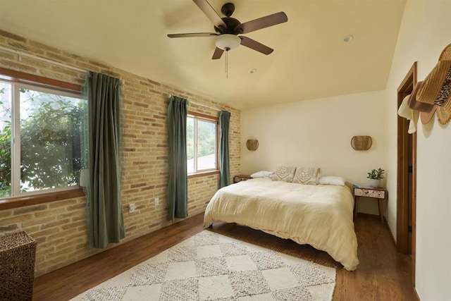 bedroom with hardwood / wood-style flooring and brick wall