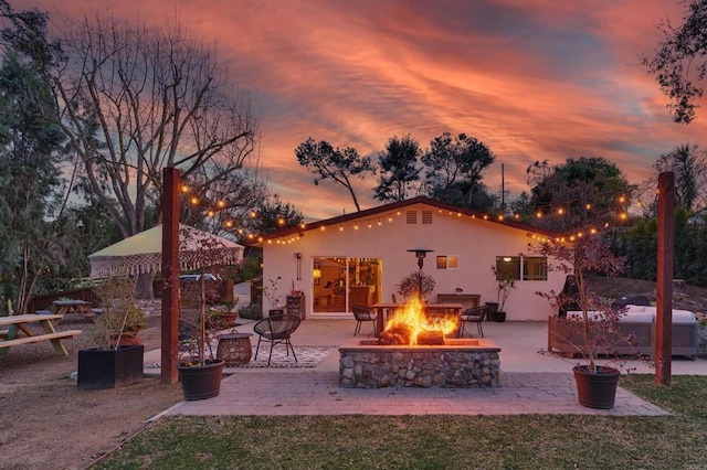 back house at dusk featuring a patio area and a fire pit