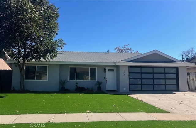 single story home with a garage, driveway, roof with shingles, stucco siding, and a front lawn