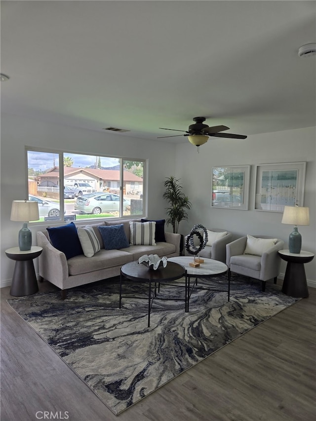 living area with a ceiling fan, baseboards, visible vents, and wood finished floors