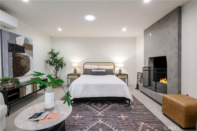 bedroom featuring a large fireplace, recessed lighting, concrete flooring, and a wall mounted air conditioner