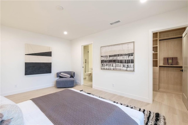 bedroom with a walk in closet, recessed lighting, visible vents, light wood-type flooring, and baseboards