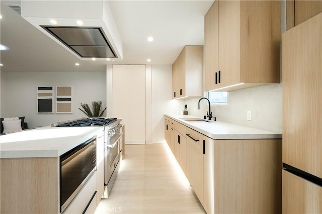 kitchen with recessed lighting, a sink, light brown cabinets, stainless steel range, and light countertops