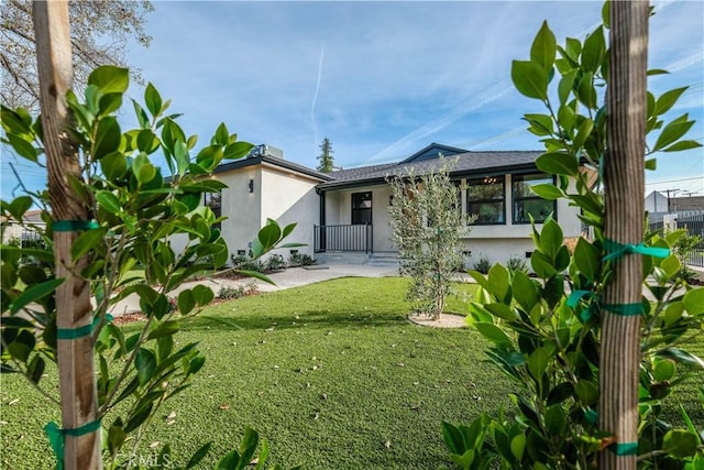 rear view of property with stucco siding and a lawn