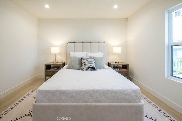 bedroom with baseboard heating, recessed lighting, light wood-style flooring, and baseboards