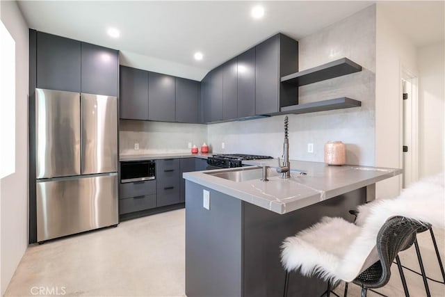kitchen featuring a breakfast bar, stainless steel appliances, finished concrete floors, a peninsula, and modern cabinets