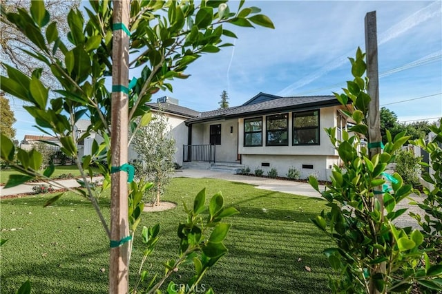 rear view of property featuring a yard, crawl space, and stucco siding