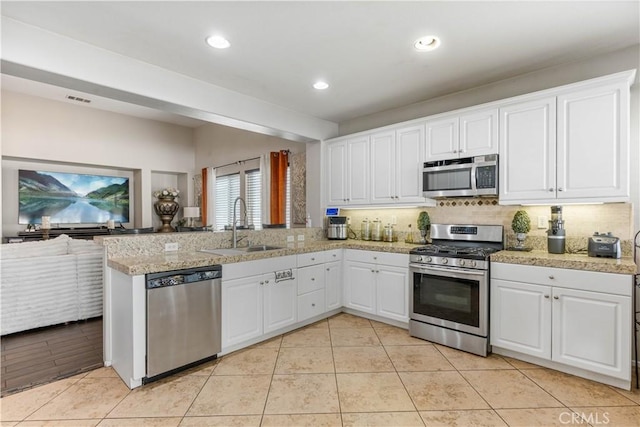 kitchen featuring white cabinetry, kitchen peninsula, sink, light tile patterned floors, and appliances with stainless steel finishes