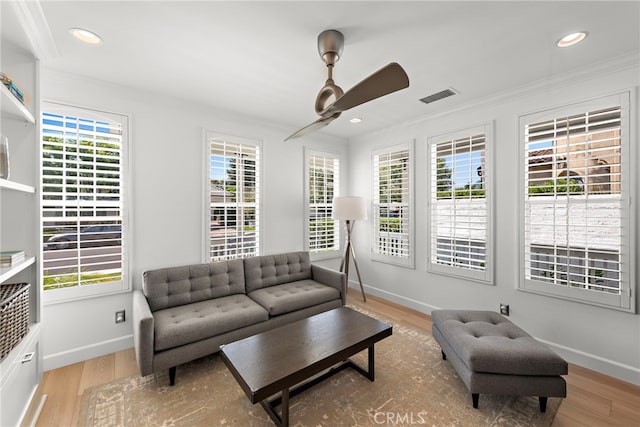 living room featuring a wealth of natural light, crown molding, and light hardwood / wood-style floors