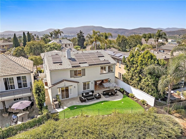 rear view of property featuring a patio, an outdoor living space, solar panels, and a mountain view