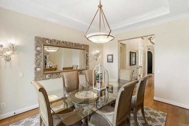 dining space featuring arched walkways, hardwood / wood-style floors, baseboards, and crown molding