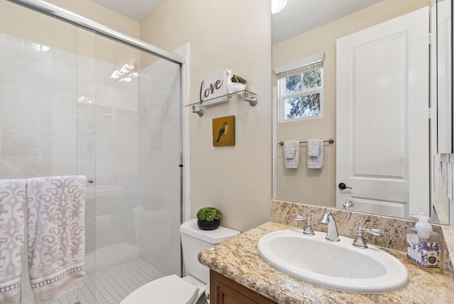 bathroom with vanity, a shower stall, and toilet