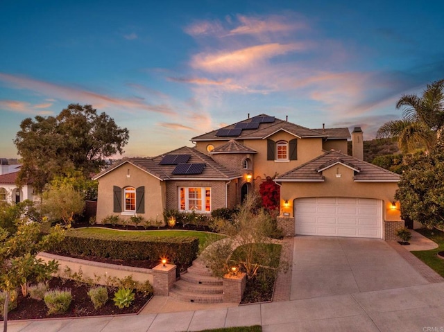 mediterranean / spanish house with driveway, a garage, a chimney, a tiled roof, and brick siding