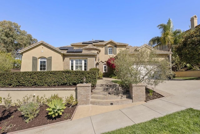 mediterranean / spanish house featuring solar panels, concrete driveway, a tile roof, an attached garage, and stucco siding