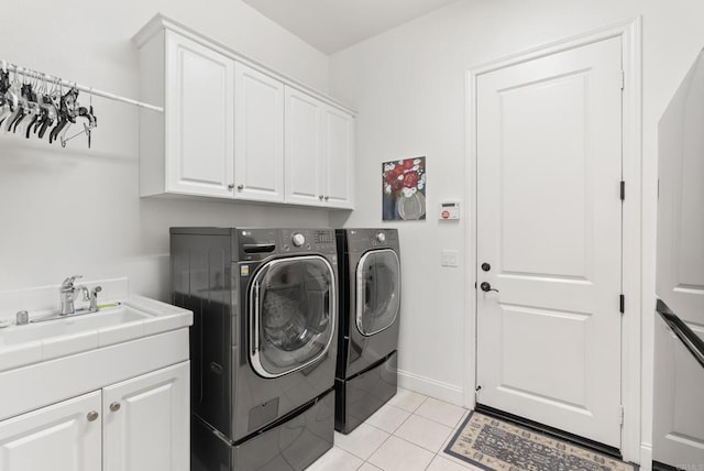 washroom featuring light tile patterned floors, a sink, baseboards, cabinet space, and washing machine and clothes dryer