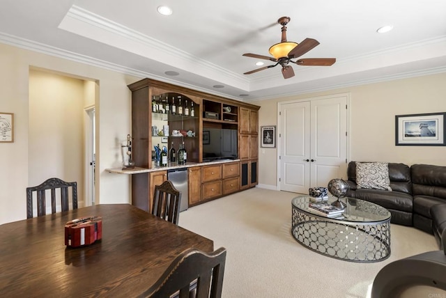 living room featuring indoor wet bar, crown molding, a raised ceiling, light colored carpet, and a ceiling fan