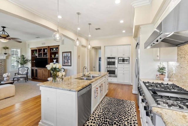 kitchen featuring visible vents, open floor plan, stainless steel appliances, wall chimney range hood, and a sink