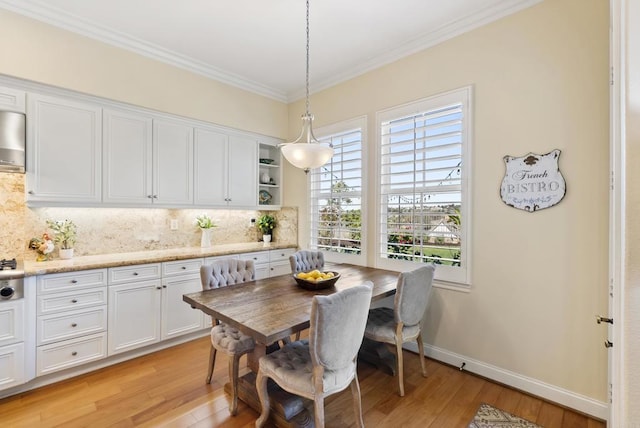 dining room with ornamental molding, light wood-type flooring, and baseboards