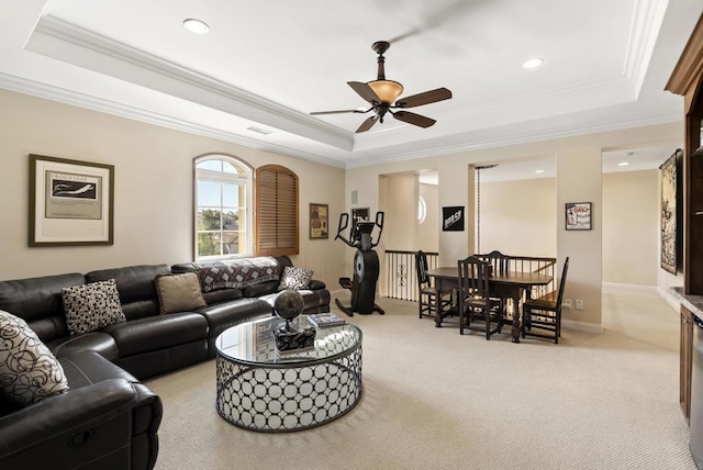 carpeted living room with ornamental molding, a tray ceiling, and baseboards