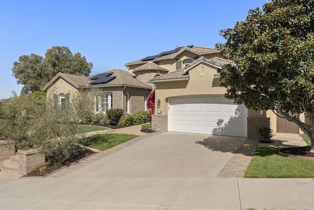 view of front facade featuring brick siding, stucco siding, solar panels, a garage, and driveway