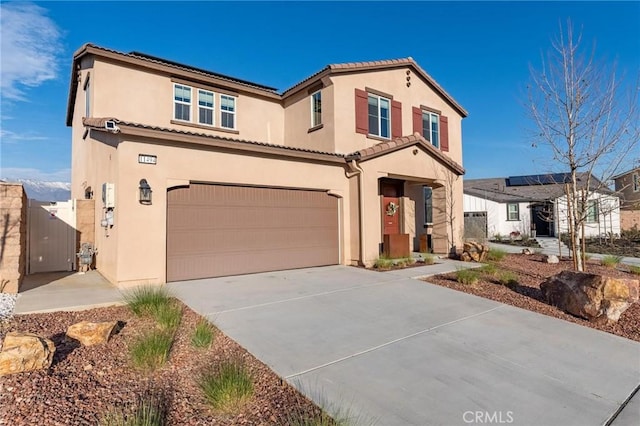 mediterranean / spanish home with a garage, driveway, a tiled roof, and stucco siding