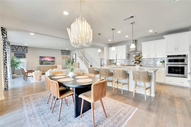 dining room featuring light wood-type flooring and an inviting chandelier